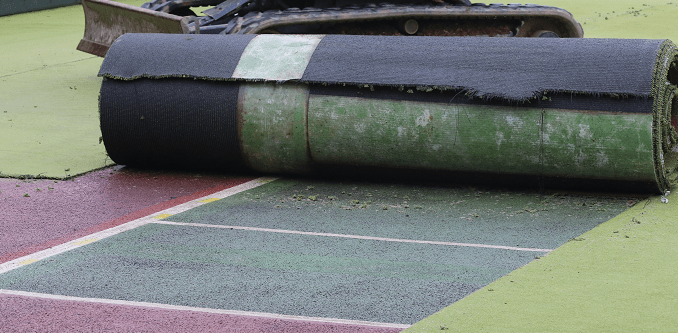 rolling up old synthetic surface with specialist machinery