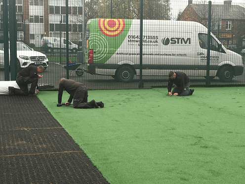 installers fitting astroturf football pitch