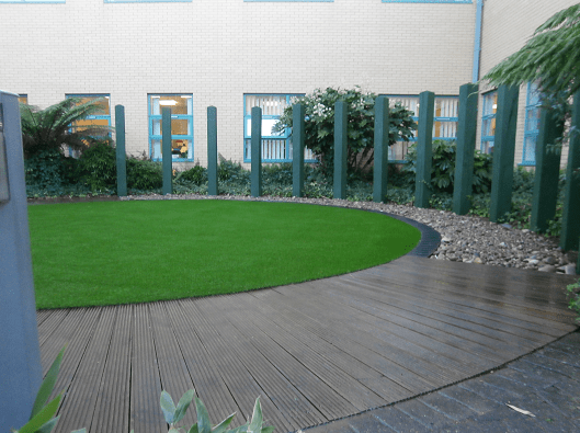 artificial grass landscaping in circle area surrounded by paving and decking