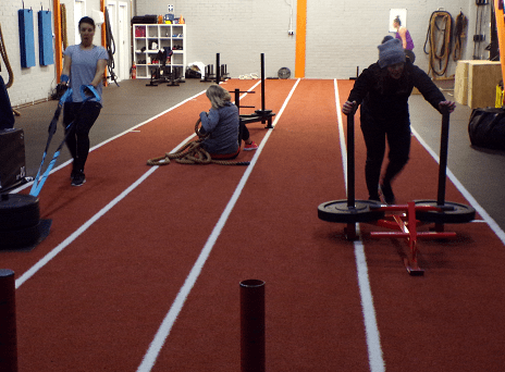 three gym goers on the sled track
