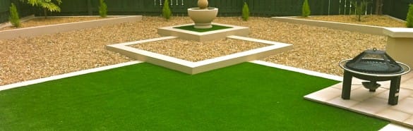 landscape garden with gravel, fire pit and sculpture around artificial turf