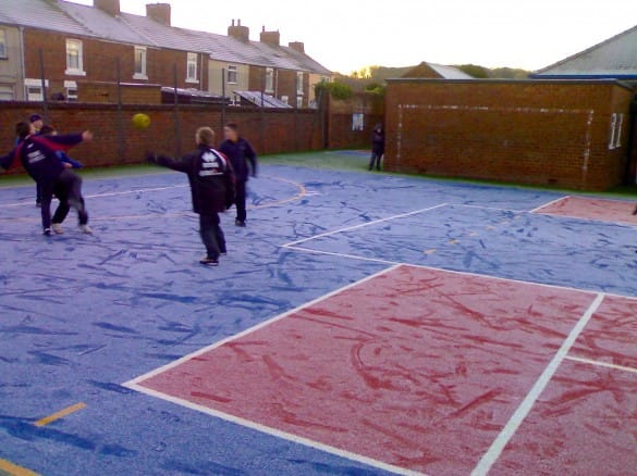 artificial turf muga in frosty weather with children playing on it