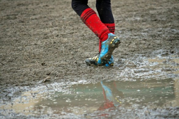 muddy soccer shoes of a child player during a football match in a playing field full of mud