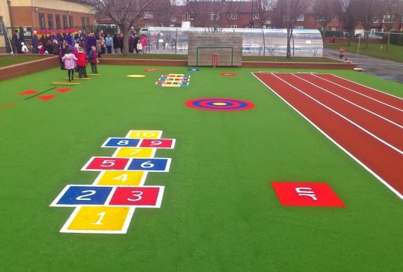 playground with hopscotch, phonics tiles, a running track and different designs on a green surface