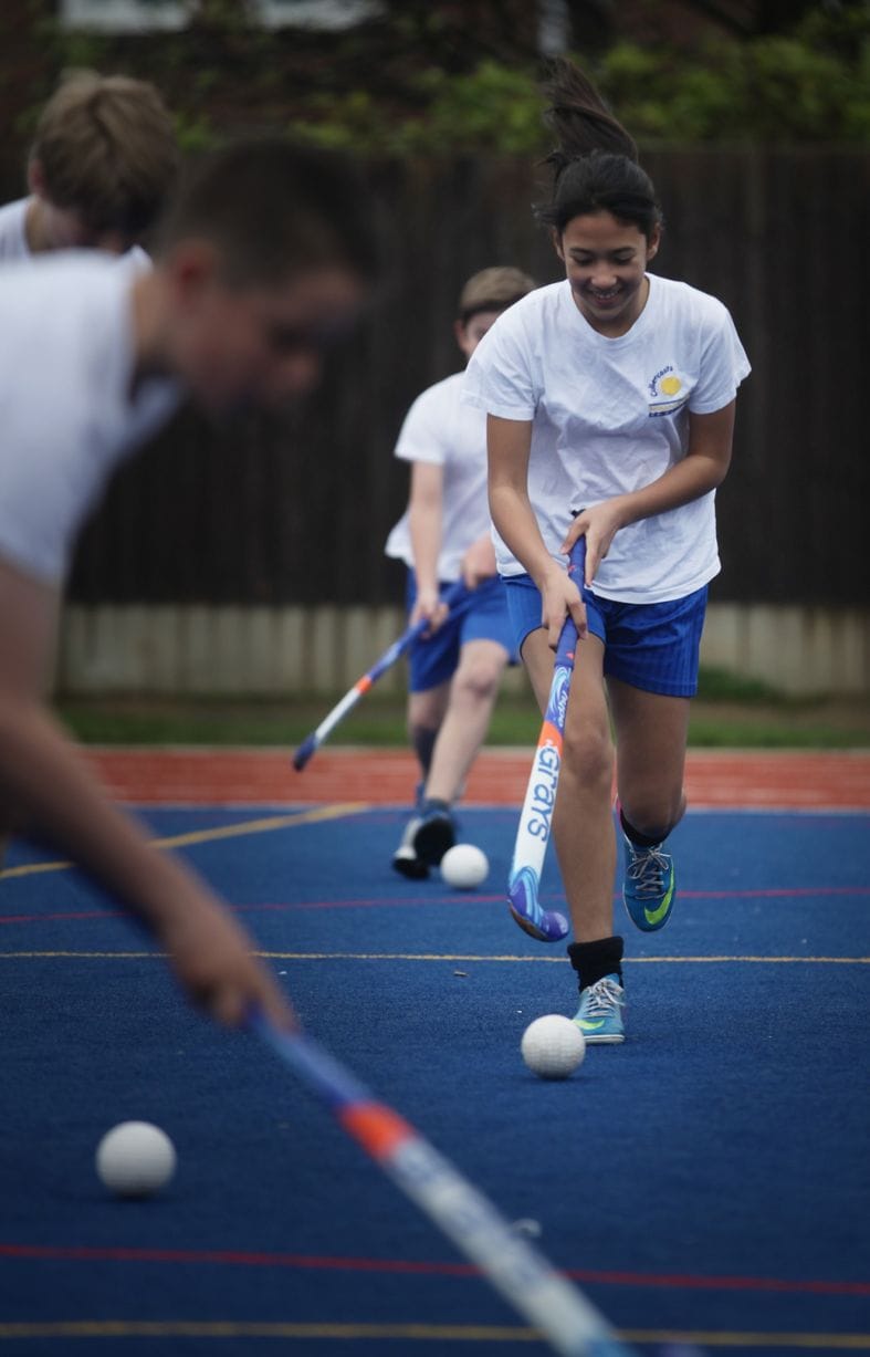 pupils playing hockey on synthetic turf muga