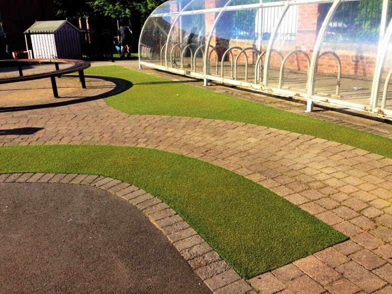 artificial grass surrounding the brick pathway