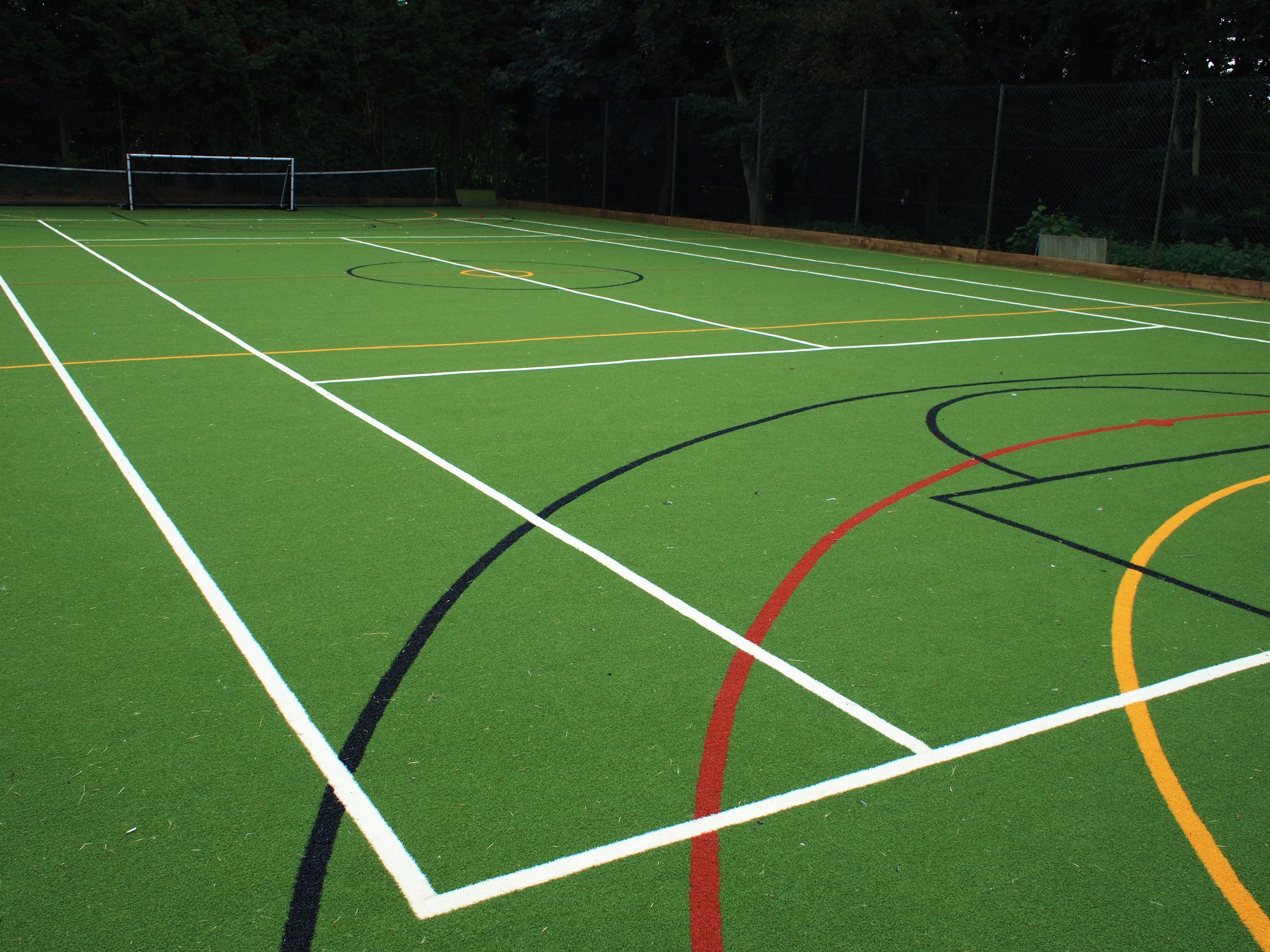 green synthetic muga pitch with black, red, yellow and white line markings