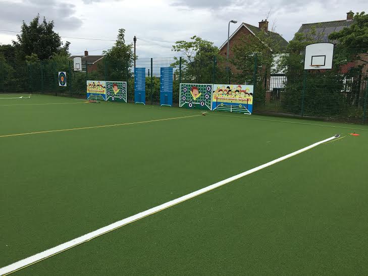 artificial turf green muga with basketball hoops at primary school 
