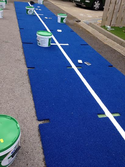 process showing the gym track being made with the white line marking being cut into the turf