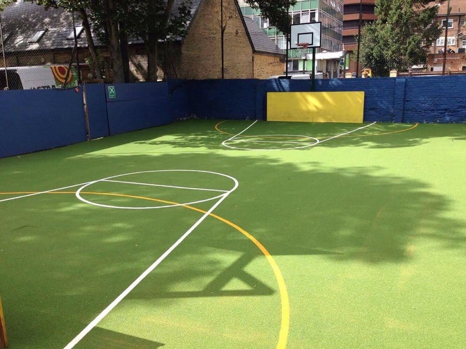 enclosed sports area at primary school showing green synthetic surface