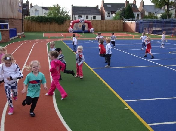 early years children playing on artificial grass primary school muga