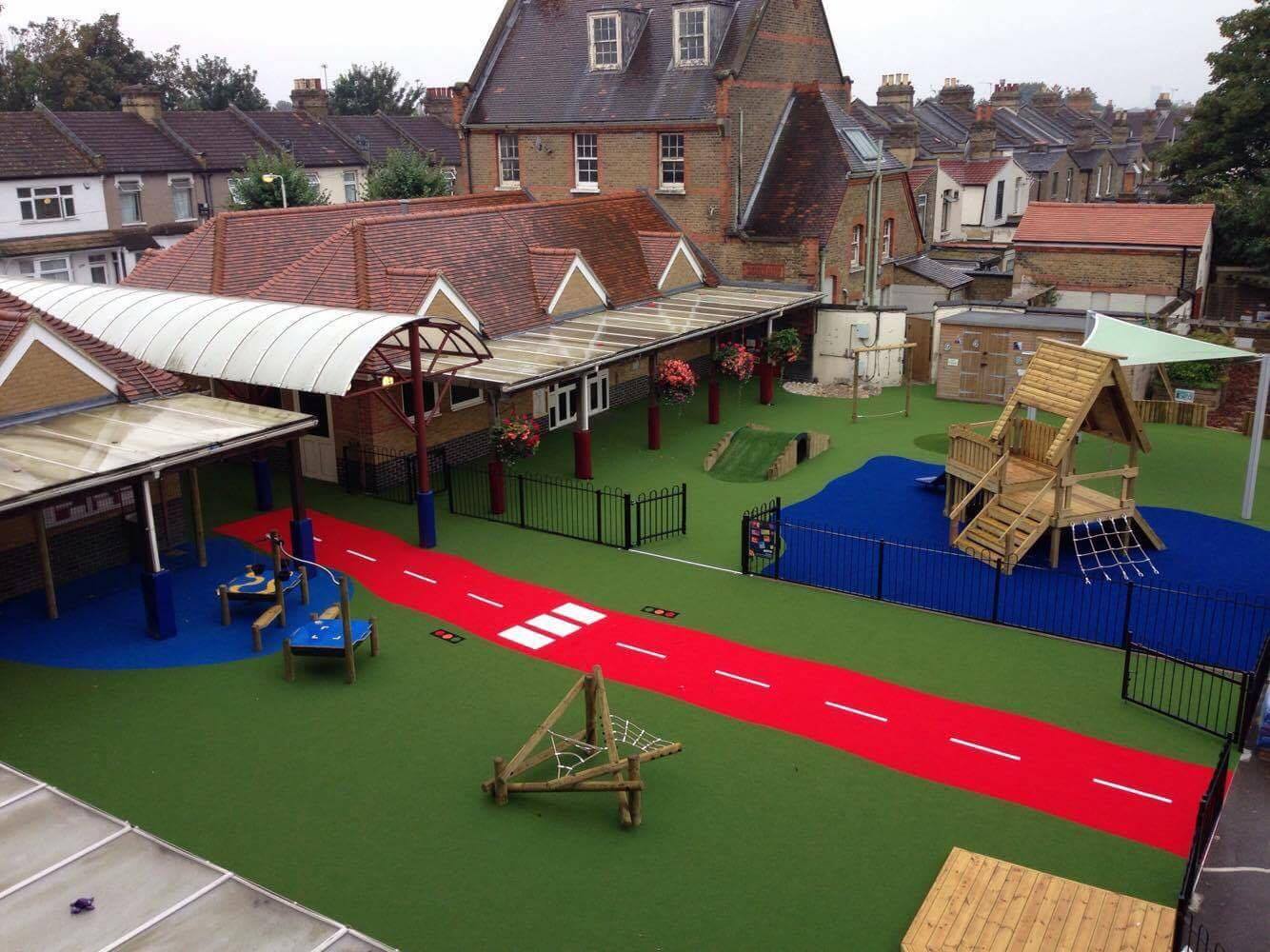 overhead view of green artificial grass playground with play area and blue and red markings