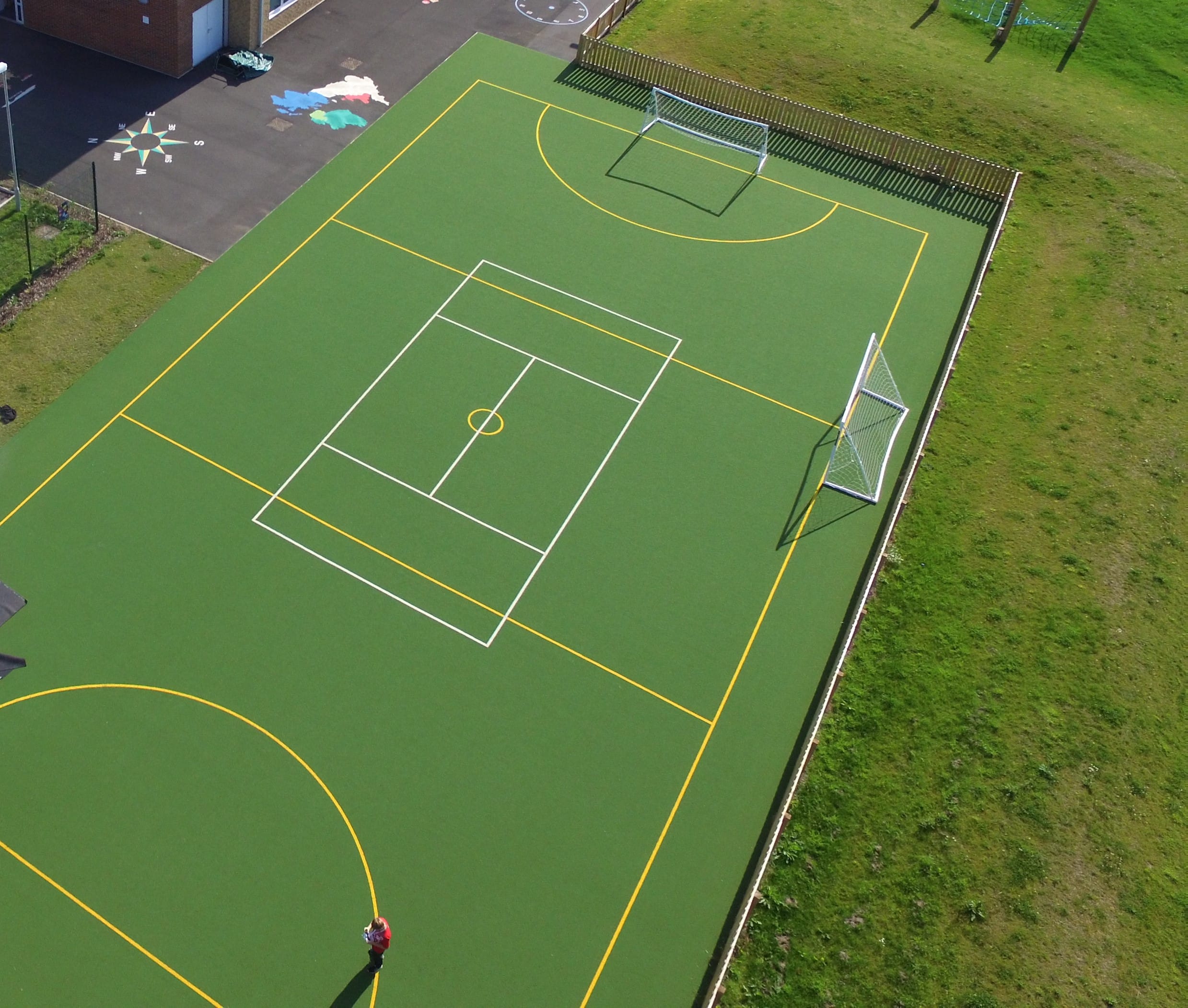 drone view of school sports surface in green with yellow and white sport markings