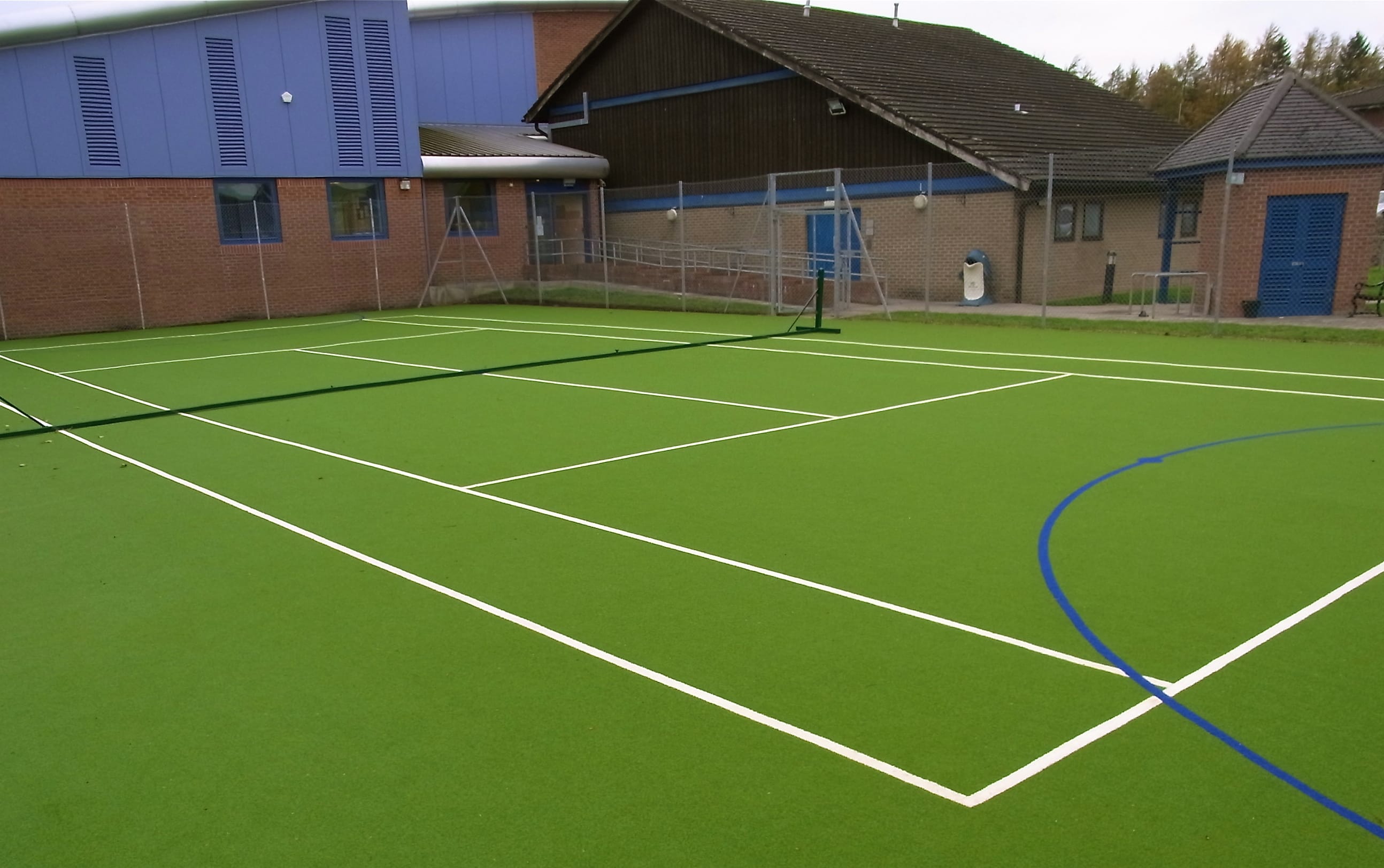 vibrant green muga being used as a tennis court
