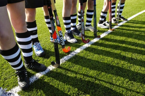image of people stood with hockey clubs on synthetic grass pitch