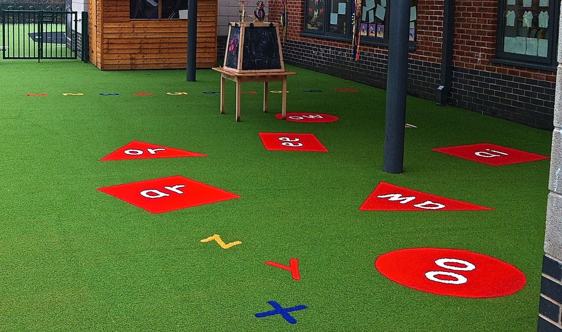 red phonics tiles and letters cut into green playground area