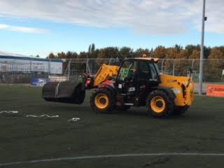 machinery transporting old rolls away from the pitch