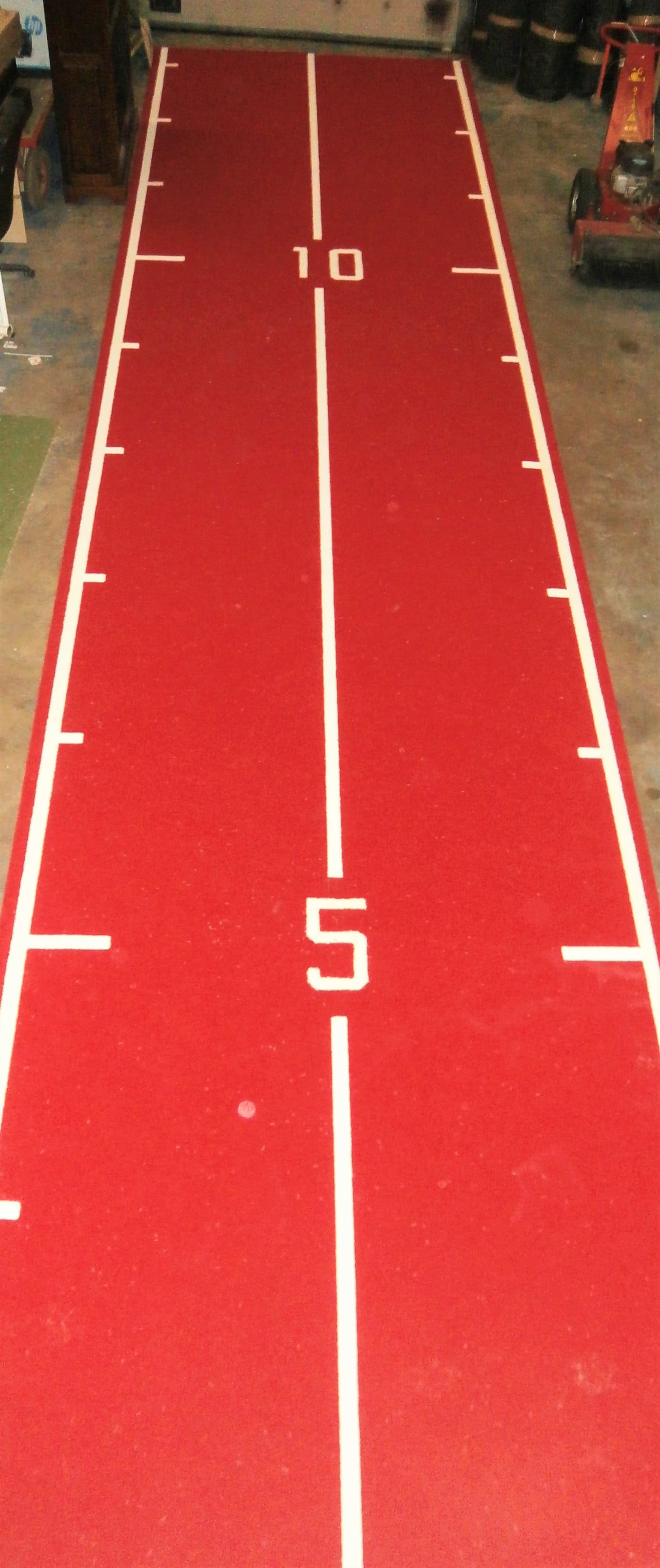 full length view of a red astroturf gym mat with white gym track markings