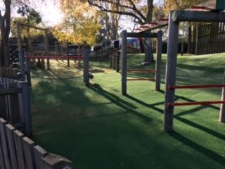 plain green artificial turf cut around existing play equipment