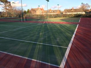 green tennis court with rust border and white markings