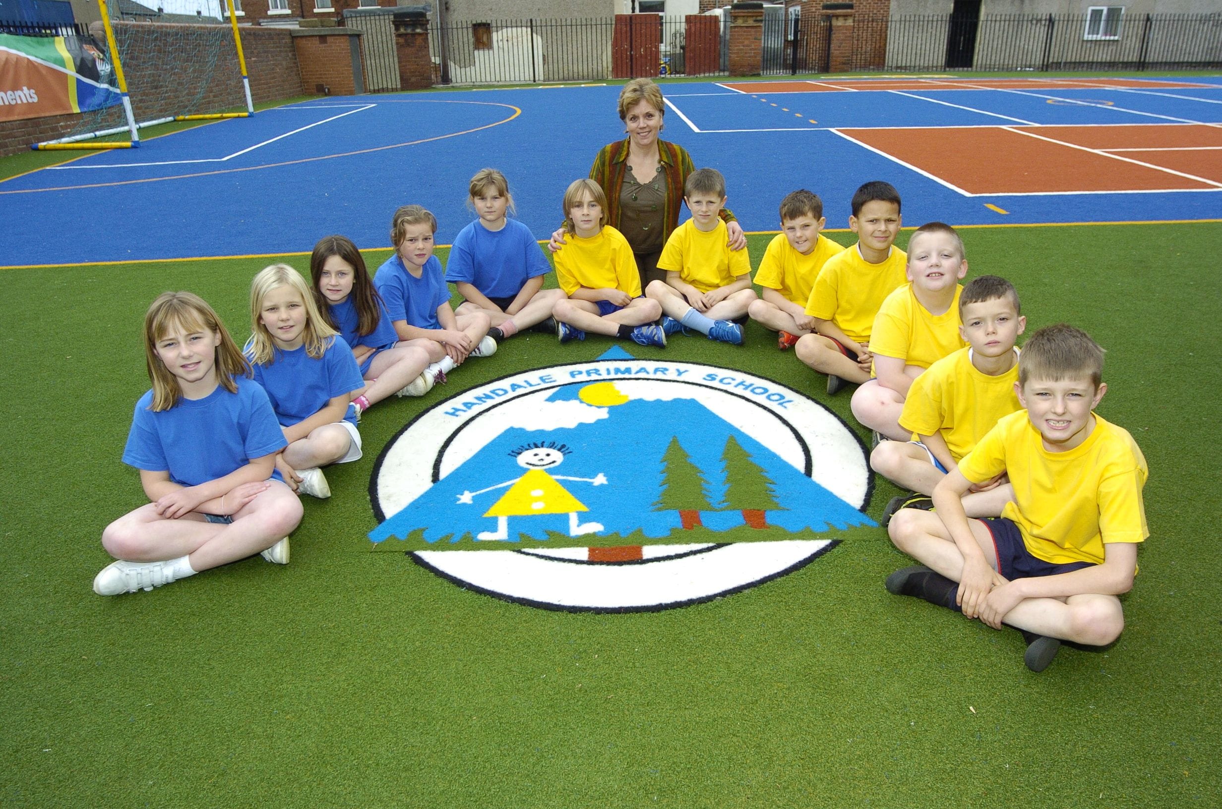 pupils sat on playground surface next to their school logo
